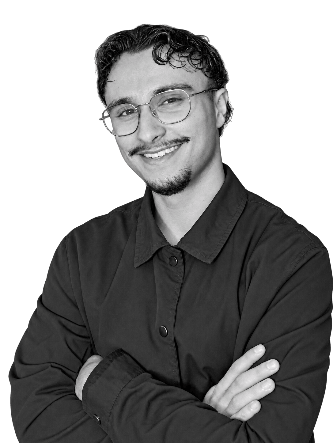 Portrait en noir et blanc d’Amine Allali : il sourit, porte des lunettes et une chemise sombre, les bras croisés.